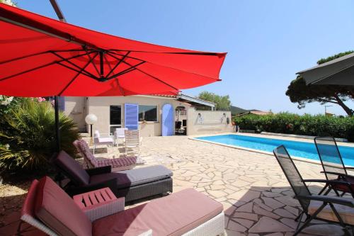 une terrasse avec un parasol rouge, des chaises et une piscine dans l'établissement Villa Les Lauriers Blancs pour 6 personnes avec piscine privée et vue mer à La Londe-Les-Maures, à La Londe-les-Maures