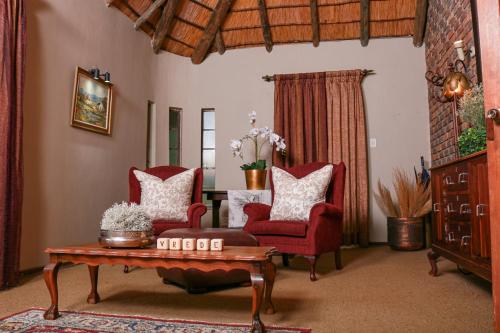 a living room with two red chairs and a coffee table at Diamantvallei Landgoed in Rayton