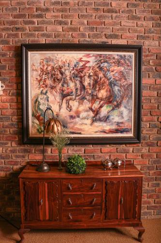 a painting of horses on a brick wall with a wooden cabinet at Diamantvallei Landgoed in Rayton