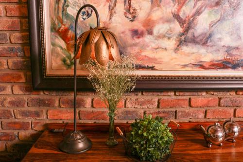 a lamp on a table next to a wall with a painting at Diamantvallei Landgoed in Rayton
