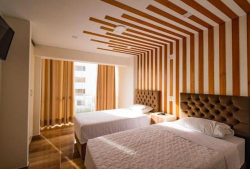 a bedroom with two beds and a large window at Hospedaje Arenas del Mar in Ilo