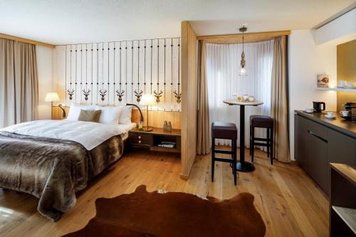 a hotel room with a bed and a table and a kitchen at Hotel Piz Buin Klosters in Klosters