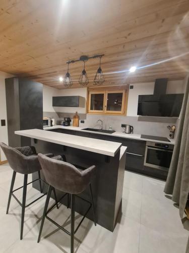 une cuisine avec une grande île et 2 chaises de bar dans l'établissement loulettaz 2, au Grand-Bornand