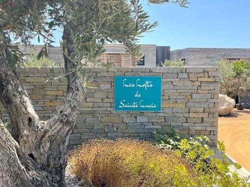 un mur en briques avec un panneau bleu sur celui-ci dans l'établissement Villa Les Lofts de Sainte Lucie, à Sainte-Lucie de Porto-Vecchio