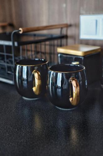 two black coffee cups with gold handles on a table at Villa Corleone in Kąty Wrocławskie