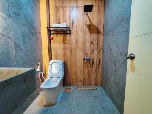 a bathroom with a toilet and a wooden wall at Kodai Trek Inn in Kodaikānāl