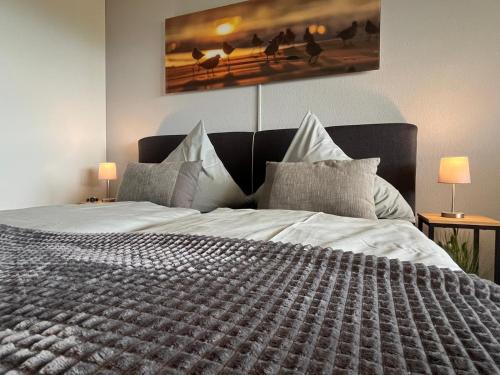 Un dormitorio con una cama grande con sábanas y almohadas blancas. en Bodensee Strandläufer Quartier, en Daisendorf