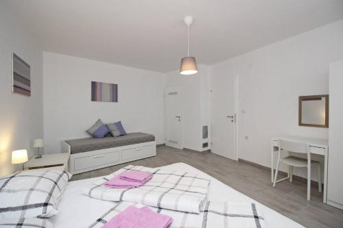 a white bedroom with two beds and a desk at House Lavanda - Kricin, underground level apartment in Baška