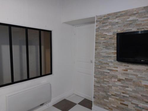 Cette chambre dispose d'une télévision à écran plat sur un mur en briques. dans l'établissement T2 Centre ville Béziers, à Béziers