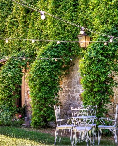 a table and chairs under an ivy covered wall at Il Giardino e la Dimora in Bomarzo