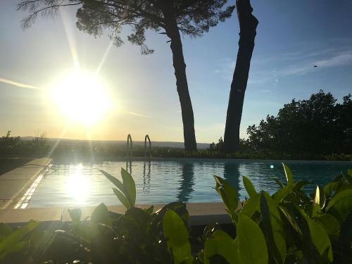 a swimming pool with the sun setting in the background at Il Giardino e la Dimora in Bomarzo