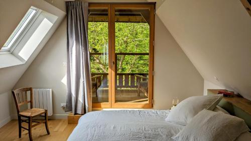 une chambre avec un lit et une grande fenêtre dans l'établissement La Maison dans les Bois - Plages 30 min, à Penquesten