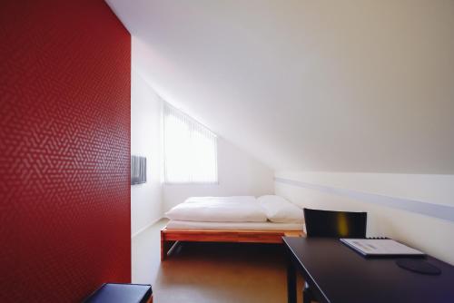 a bedroom with a bed with a red wall at Wirtshaus Rütihof in Gränichen