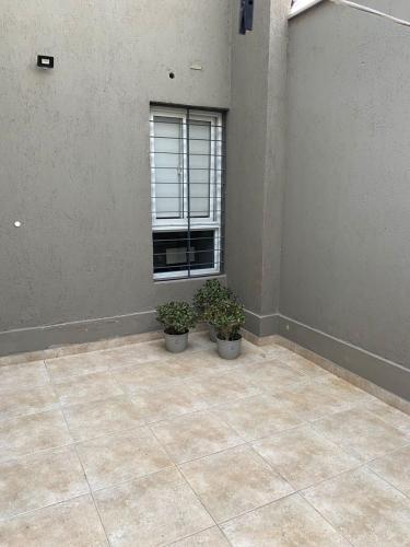 a room with two potted plants and a window at Departamento para 5 personas con cochera in Godoy Cruz