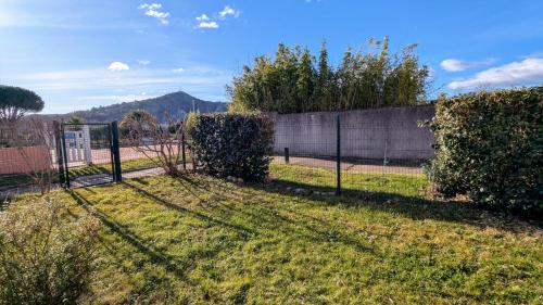 a fence in the grass next to a wall at Bel appartement T3 avec jardin privatif et piscine commune in Ruoms