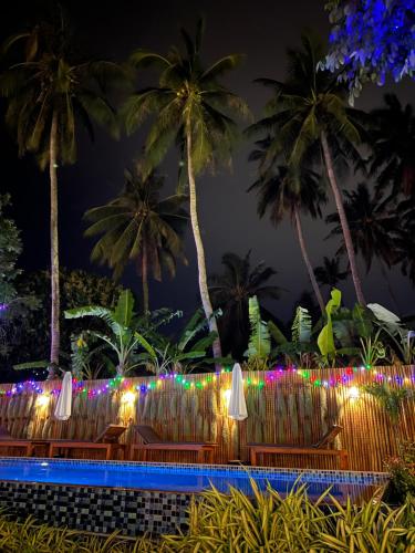 a resort pool with chairs and palm trees at night at U OLIVE Hotel in Ban Nua