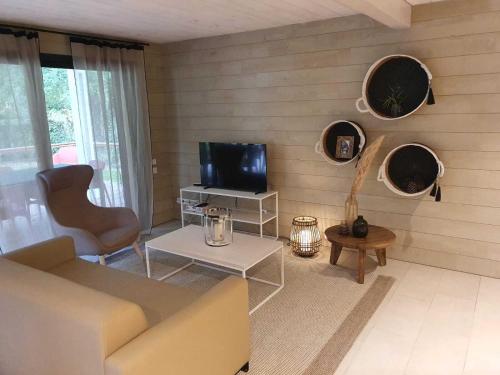 a living room with a couch and a tv at Grand Chalet de Pitrot in Lacanau