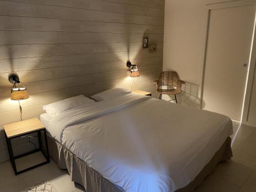 une chambre avec un grand lit blanc et deux lampes dans l'établissement Grand Chalet de Pitrot, à Lacanau