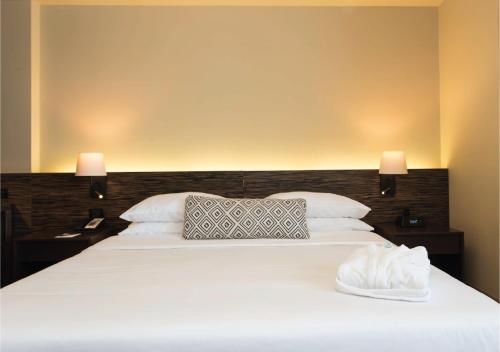a bedroom with a large white bed with two lamps at Movich Hotel de Pereira in Pereira
