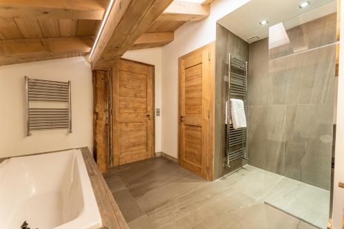 La salle de bains est pourvue d'une baignoire et d'une douche à l'italienne. dans l'établissement Chalet les Oyats - SKI IN SKI OUT, à Megève