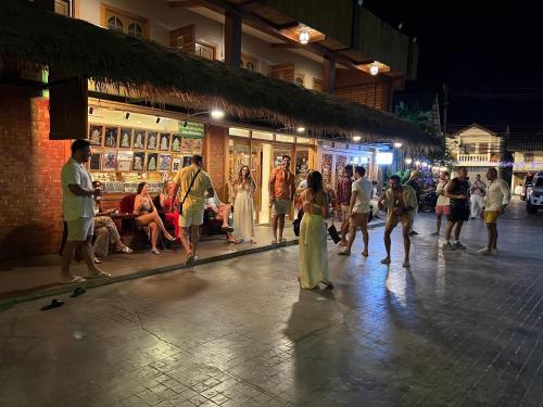 a group of people walking down a street at night at U OLIVE Hotel in Ban Nua