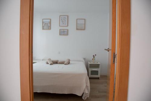 a bedroom with a bed with white sheets and a mirror at Jamaica Beach House in Puebla de Farnals