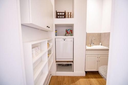 une cuisine avec des armoires blanches et une laveuse et une sécheuse dans l'établissement Maison de maitre et son parc, à Toulouse