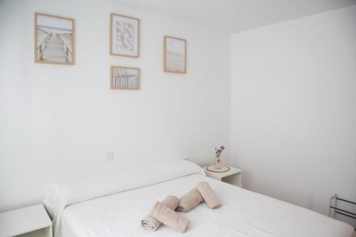 a white room with a bed with two wooden logs on it at Jamaica Beach House in Puebla de Farnals