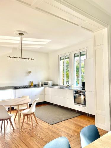 une cuisine avec des armoires blanches et une table et des chaises dans l'établissement Maison de maitre et son parc, à Toulouse