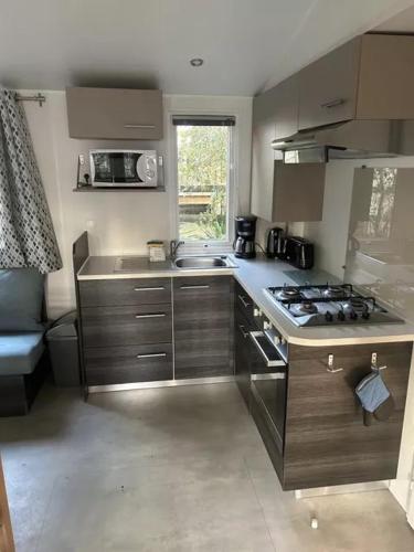 Il comprend une petite cuisine équipée d'une cuisinière et d'un évier. dans l'établissement Bonne Anse Plage Mobile home 3 chambres 8 personnes, aux Mathes