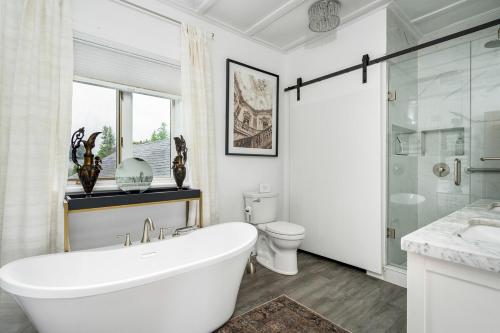 a white bathroom with a tub and a toilet at 3bed 2bath heritage duplex - Prime Location in Collingwood