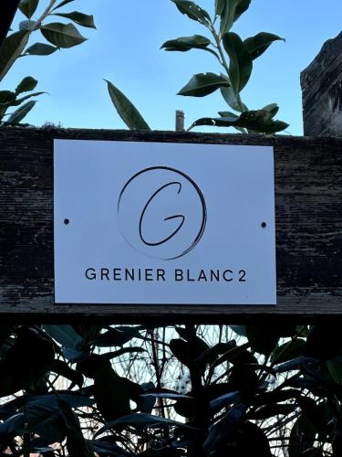 a sign on a wooden fence with a plant at Grenier Blanc2 Elegante Mansarda in San Vicenzo di Galliera