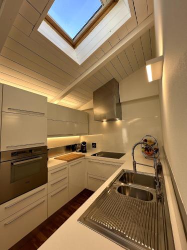 a kitchen with a sink and a skylight at Grenier Blanc2 Elegante Mansarda in San Vicenzo di Galliera