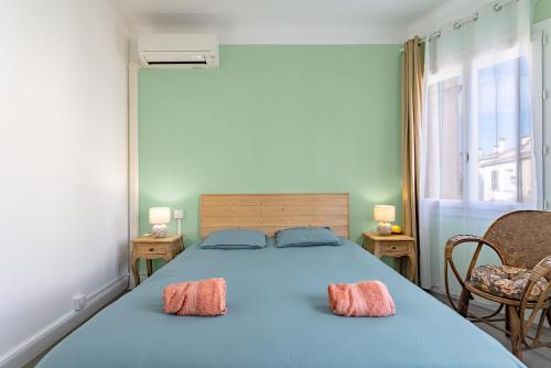 a bedroom with a blue bed with two pink pillows at L'Oreneta, Le Boulou, idéal curiste in Le Boulou