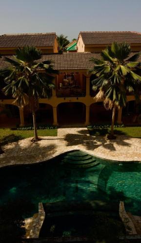 a house with palm trees in front of a swimming pool at Grand Appartement avec Piscine Jardin de la Lagune in Saly Portudal