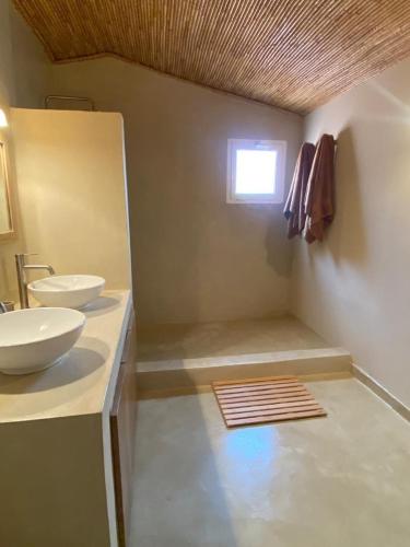 a bathroom with two sinks and a window at Grand Appartement avec Piscine Jardin de la Lagune in Saly Portudal