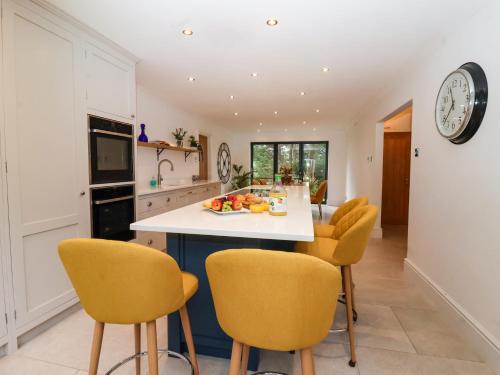 a kitchen with yellow chairs and a kitchen island at The Pines in Skipton