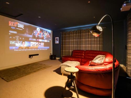 a living room with a red couch and a big screen at The Pines in Skipton