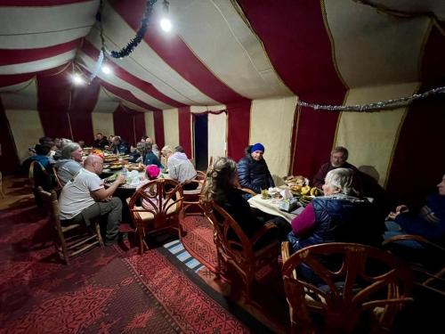 a group of people sitting at tables in a tent at Camp Sahara Feeling in El Gouera