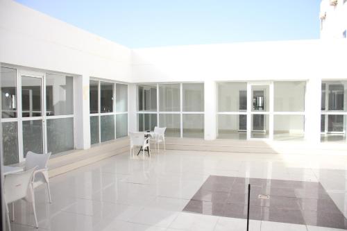 a room with white chairs and a table and windows at HOTEL NAKHIL in Nouadhibou