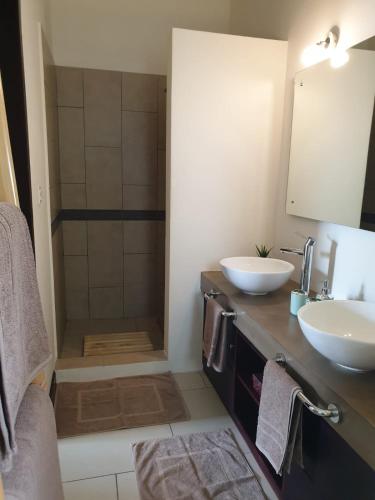 a bathroom with two sinks and a shower at Chez Blandine et Sylvain in Cascavelle