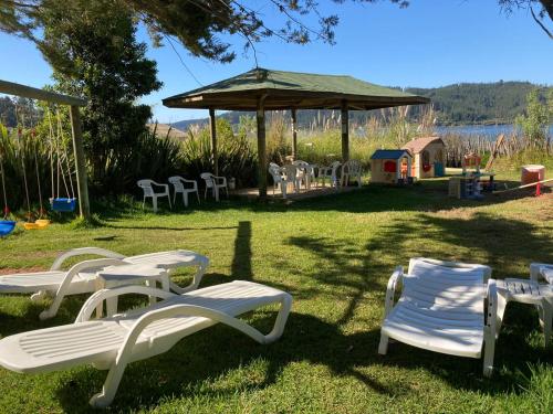 a group of white lawn chairs and a gazebo at Cabañas Parador del Aguila - Lago Vichuquén in Vichuquén