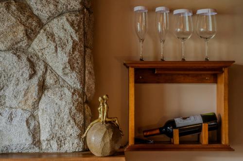 a bottle of wine and wine glasses on a shelf at Mirante da Colyna Hotel & SPA in Monte Verde