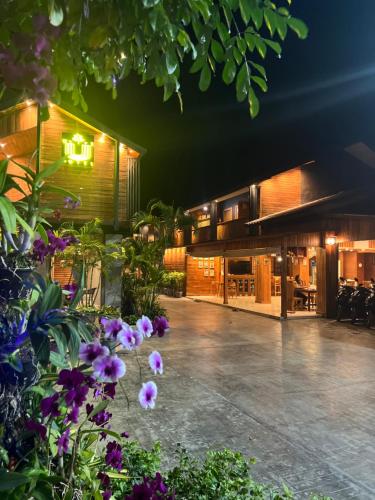 a house with a courtyard at night with purple flowers at U OLIVE Hotel in Ban Nua