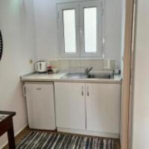 - une cuisine avec des placards blancs, un évier et 2 fenêtres dans l'établissement Poseidon beach Apartments, à Paleokastritsa