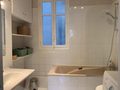 une salle de bain blanche avec une baignoire et un lavabo dans l'établissement Appartement vue sur la tour Eiffel, à Paris