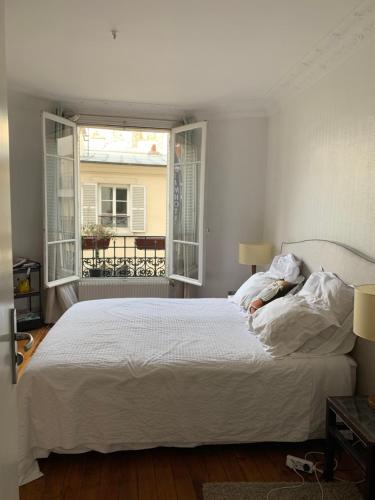 une chambre avec un lit blanc et une fenêtre dans l'établissement Appartement vue sur la tour Eiffel, à Paris