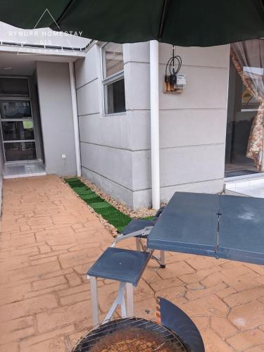 a picnic table and an umbrella in front of a house at Rynurr Homestay A Famosa near Waterpark in Kampong Pulau Sebang