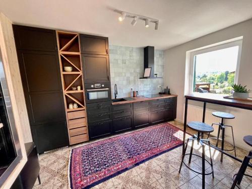 a kitchen with black cabinets and a large window at Chalet beim Georgi Schloss in Ehrenhausen
