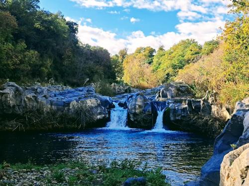 a waterfall in a river with rocks and trees at Casa Ruffo in Francavilla di Sicilia